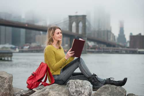 Donna con libro seduta vicino al ponte