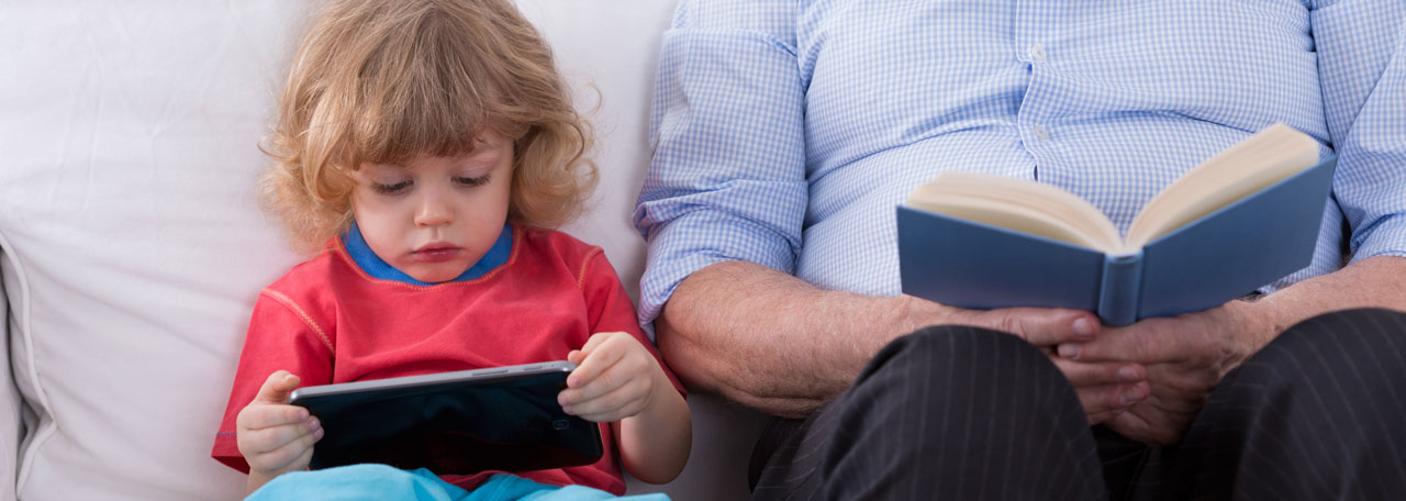 Un enfant et un homme lisent un livre et sur une tablette