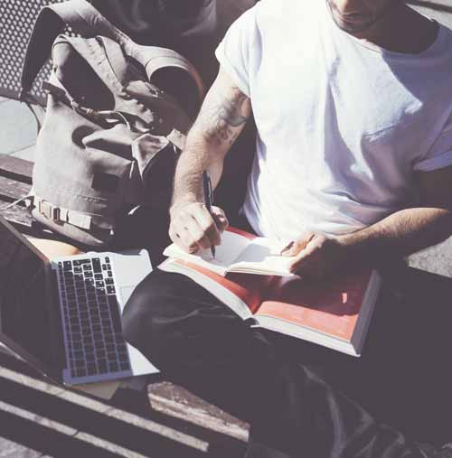 Mężczyzna czyta książkę, obok laptop