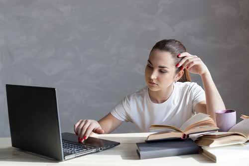 Kobieta pisze tekst z książkami i laptopem