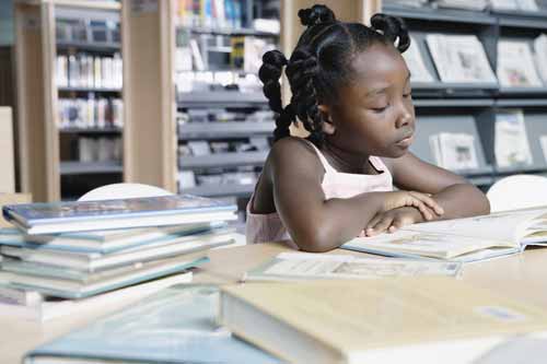 Klein meisje leest in bibliotheek