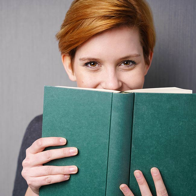 Vrouw verschuilt gezicht achter boek